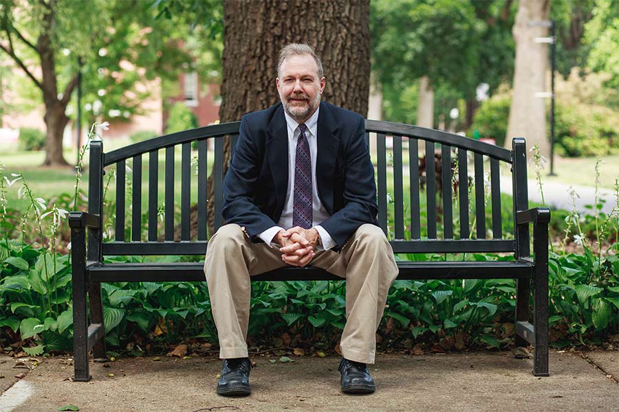 Dr. Nicholas Meriwether is pictured sitting on a bench smiling