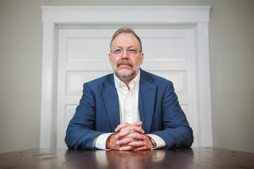 Dr. Nicholas Meriwether is pictured sitting at a desk with his hands crossed