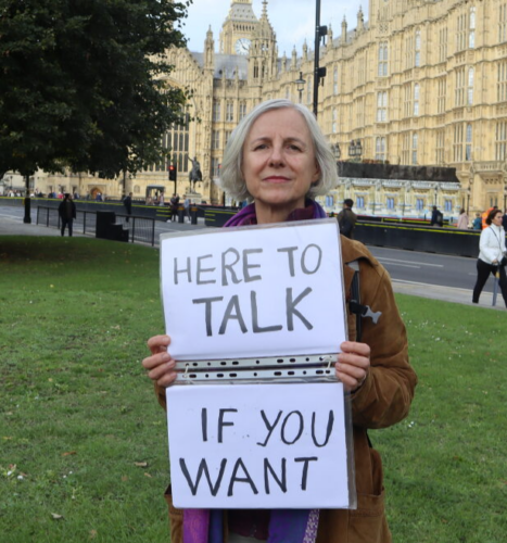 Livia Tossici-Bolt holds a sign that reads 'here to talk if you want.'